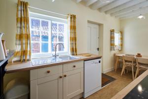 a kitchen with a sink and a window and a table at Host & Stay - Park View in Brafferton