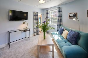 a living room with a blue couch and a tv at Host & Stay - Park View in Brafferton