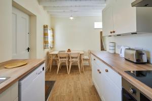 una cocina con armarios blancos y una mesa con sillas. en Host & Stay - Park View en Brafferton
