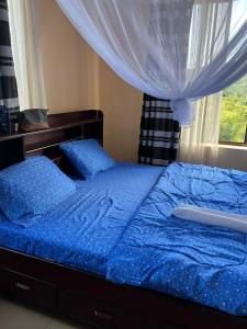 a blue bed with blue sheets and a window at MHALO BEACH LODGE 