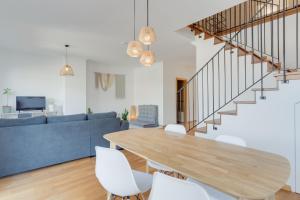 a living room with a wooden table and white chairs at Alta do Garajau I in Caniço