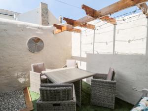 a patio with a table and chairs and a wall at Bonnie's Retreat in Amble