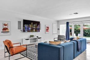 Una sala de estar con un sofá azul y dos sillas. en Luxury 3 Bedroom Home 5 minutes to Ocean with Heated Pool, en Hollywood