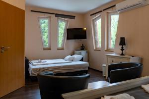 a hotel room with a bed and a tv and windows at Accomo Apartmanház in Siófok