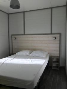 ein Bett mit weißen Laken und Kissen in einem Zimmer in der Unterkunft Le Domaine du Scorff - hébergements insolites chalets 4 à 6 personnes et roulottes in Kernascléden + 21 Fotos