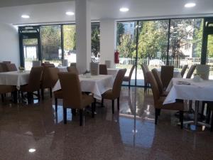 een eetkamer met witte tafels, stoelen en ramen bij Malena in Goražde