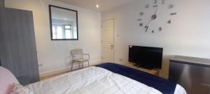 a bedroom with a bed and a flat screen tv at Feel at Home in Elmers End
