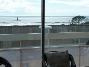 - une vue sur l'océan depuis une fenêtre avec une chaise dans l'établissement Studio avec vue sur mer à Granville. Plage à 3 min, à Granville