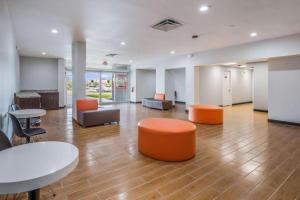 una oficina con mesas, sillas y asientos naranjas en OYO Hotel Orlando Airport, en Orlando