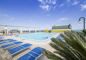 een zwembad op een cruiseschip met blauwe stoelen bij Residence Cristoforo Colombo - Carraro Immobiliare - Family Apartments in Caorle