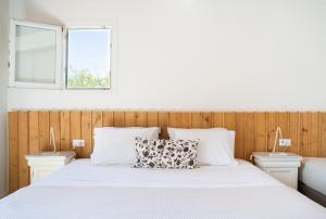 a bedroom with a white bed with two windows at Rhenia Hotel in Tourlos