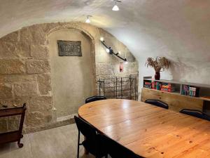 a wooden table in a room with a stone wall at La petite maison aux volets bleu - Montpellier in Montpellier