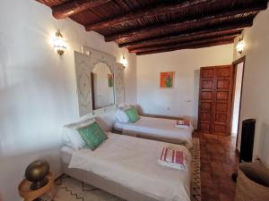 ein Wohnzimmer mit 2 Betten und einem Spiegel in der Unterkunft Maison Mimosa, lovely 3 bedroom villa with a heated pool in Essaouira