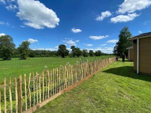 a fence with wooden poles in a field at Pipowagens bij Pannenkoekenrestaurant & Camping De Koppenjan 'Een uniek verblijf met kinderspeelboerderij' in Jubbega-Schurega
