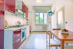 a kitchen with red cabinets and a table with a bowl of fruit at Clelia Apartments in Parma