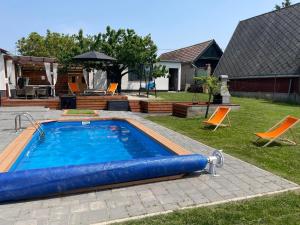 una piscina in un cortile con sedie e una casa di Loft Paradise a Győr