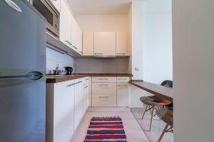 uma pequena cozinha com armários brancos e uma mesa em Apartmani na Plaži em Risan