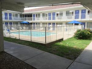 Motel 6-Ardmore, OK في أدمور: مسبح امام مبنى فيه مظلات