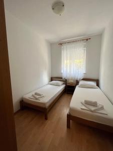 2 camas en una habitación pequeña con ventana en Apartments Karma, en Novalja