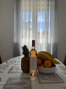 una botella de vino y un bol de fruta en una mesa en Apartments Karma en Novalja