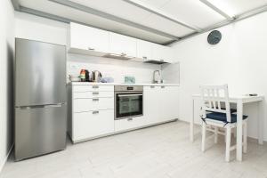 a kitchen with white cabinets and a stainless steel refrigerator at Sea Loft Quinto - A due passi dal mare in Genoa