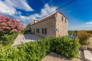 a brick building with pink flowers and bushes at Joe in Čilipi