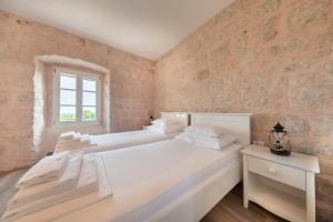 two beds in a white room with a window at Joe in Čilipi