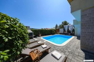 a backyard with a pool and chairs and a swimming pool at Monty in Pridraga