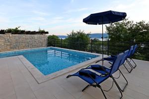 a pair of chairs and an umbrella next to a swimming pool at Lurda in Linardići
