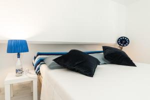 a white bed with black pillows and a blue lamp at Sea Loft Quinto - A due passi dal mare in Genoa