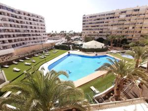 Una gran piscina con palmeras frente a un edificio. en Los Molinos 735, en Maspalomas
