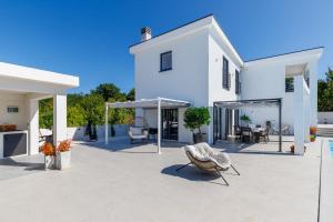 a white house with a patio with chairs and umbrellas at Valhalla in Barat