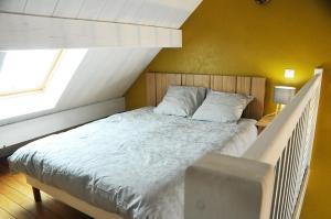 um quarto com uma cama grande e lençóis brancos em La Maison de Vinciane em Maligny
