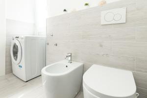 a bathroom with a toilet and a washing machine at Sea Loft Quinto - A due passi dal mare in Genoa
