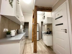 a kitchen with white cabinets and a staircase at MMRent Wild Room in Gdańsk