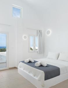 a white bedroom with a bed and a window at VOCA HOTEL & SUITES in Kamari
