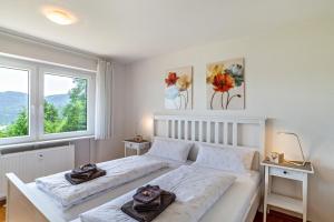 a white bedroom with two beds and two windows at Merzel's schöne Aussicht in Bühlertal