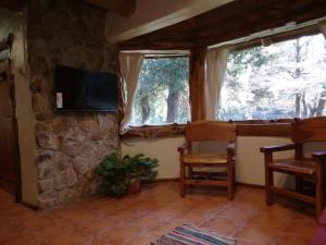 a living room with a stone wall and a tv at El viaje 2 in San Carlos de Bariloche