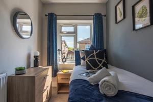 a bedroom with a bed with blue curtains and a window at Spacious Southampton House Sanctuary in the City in Southampton
