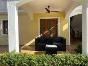 un sofá negro sentado en el porche de una casa en 1BHK Luxury Homestay In Betalbatim, South Goa en Marmagao