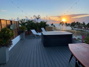una terraza con bañera de hidromasaje, sillas y puesta de sol en Ultravioleta Boutique Residences en Cabarete