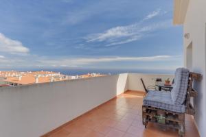 a balcony with a chair and a table on a roof at Alta do Garajau I in Caniço