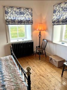ein Schlafzimmer mit einem Bett und einem Heizkörper und zwei Fenstern in der Unterkunft Traditional Donegal house on the Wild Atlantic Way in Burtonport