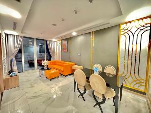 a living room with an orange couch and a table and chairs at Vinhome Central Park Apartment in Ho Chi Minh City