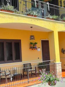 Casa amarilla con balcón con sillas y flores en Le Camerette di Edda, en Cassino