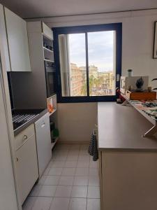 eine Küche mit einem großen Fenster und eine Küche mit weißen Geräten in der Unterkunft Le Bel Air in Canet-en-Roussillon