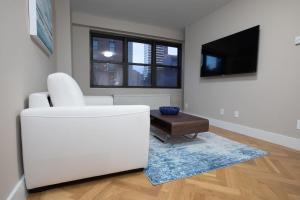 a living room with a white couch and a tv at Cozy Apartment in Upper East Side in New York