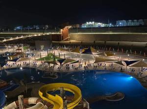 een groot zwembad 's nachts met een menigte mensen bij قريه اكوا فيو - الساحل الشمالى - الكيلو91 in El Alamein