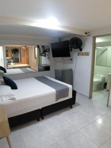 a bedroom with a bed and a tv and a bathroom at Hotel Urbano 70 in Medellín