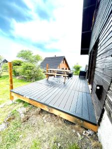 une terrasse en bois avec une table de pique-nique à côté d'un bâtiment dans l'établissement La cabane au pied des pistes, à Chastreix